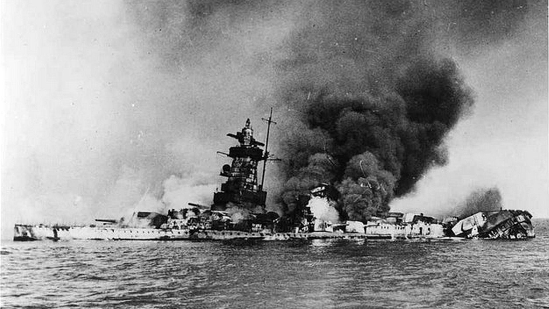 Schwarzweißbild des Panzerschiffs Graf Spee, das in Flammen steht.