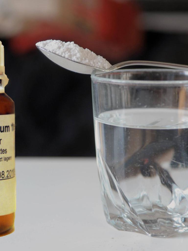 Ein braunes Arzneimittelglas mit Pentobarbital-Natrium, daneben ein gefülltes Wasserglas, auf dem ein Löffel mit dem Pulver liegt. Das tödlich wirkende Mittel wird in der Schweiz beim assistierten Suizid verwendet
