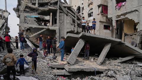 Palästinenser blicken auf die Trümmer eines durch israelische Luftangriffe zerstörten Hauses in Chan Junis im Gazastreifen. 