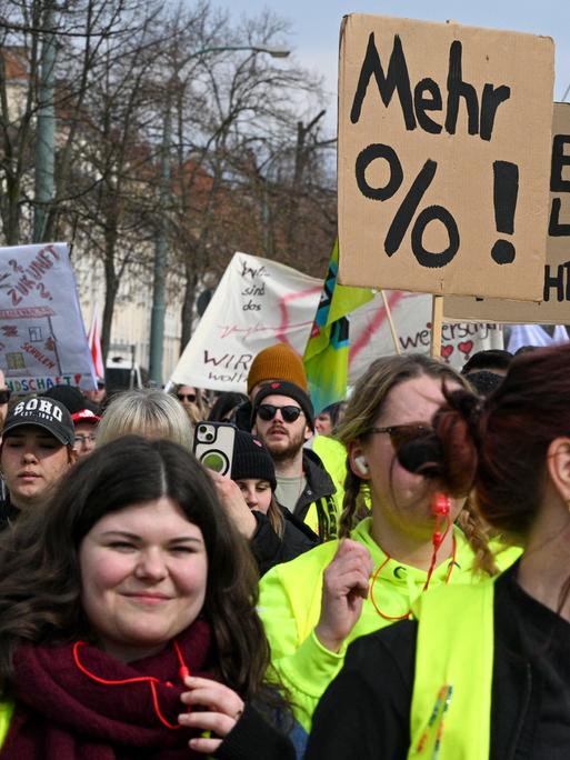 Demonstranten laufen mit Pappschildern und Wanrwesten bei der Fortsetzung der Tarifverhandlungen für den öffentlichen Dienst in einem Zug durch Potsdam.