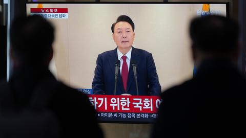 Menschen in Seoul schauen auf einen Fernsehbildschirm.