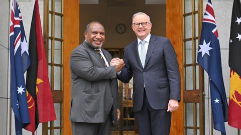 Australiens Premierminister Anthony Albanese (r.) und Papua-Neuguineas Premierminister James Marape posieren vor dem Eingang eines Gebäudes mit ineinandergelegten Händen und schauen in die Kamera