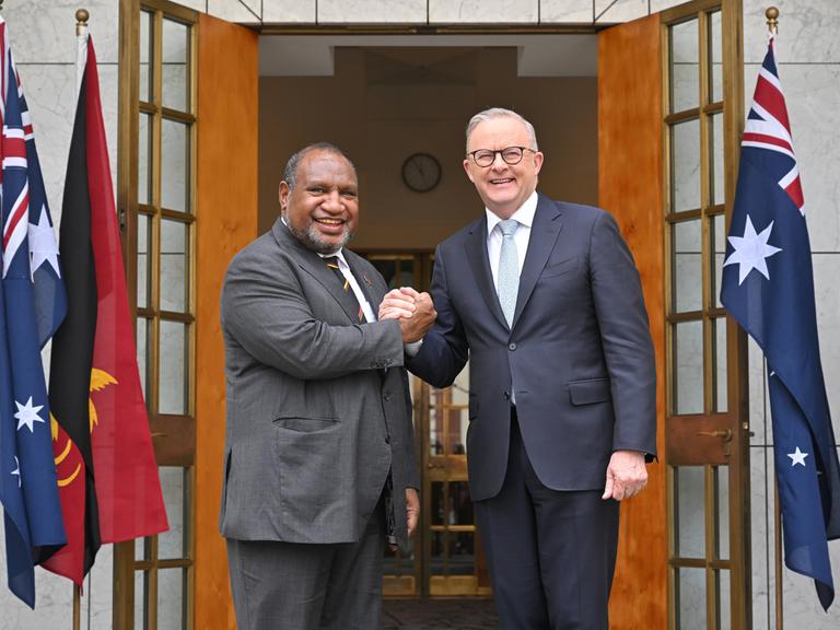 Australiens Premierminister Anthony Albanese (r.) und Papua-Neuguineas Premierminister James Marape posieren vor dem Eingang eines Gebäudes mit ineinandergelegten Händen und schauen in die Kamera