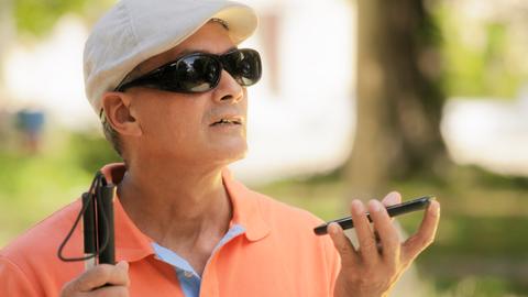 Ein blinder Mann spricht in ein Smartphone.