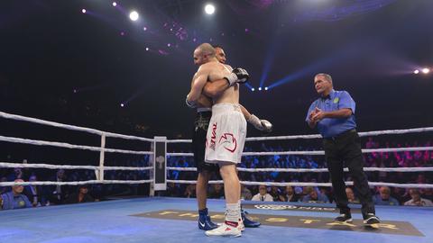 Zwei Boxer - Tim Tszyu and Joel Camilleri - stehen in einem Boxring nach einem Kampf und umarmen sich. Neben ihnen steht ein Ringrichter. Zwei Boxer - Tim Tszyu and Joel Camilleri - stehen in einem Boxring nach einem Kampf und umarmen sich. Neben ihnen steht ein Ringrichter.