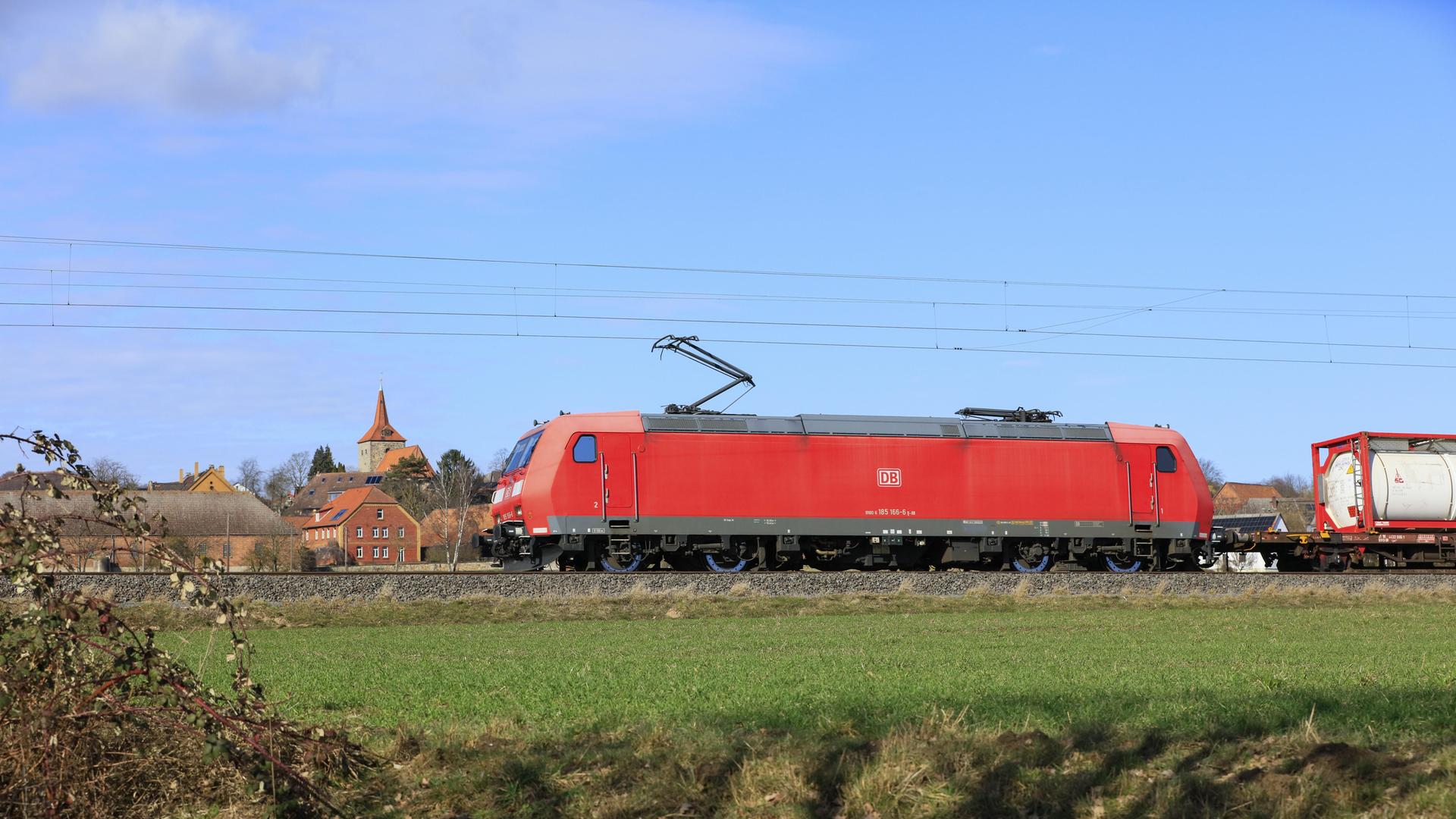 Güterzug mit Lokomotive der DB Cargo der Baureihe 185 Bombardier Traxx F140 AC1 auf der Bahnstrecke Hannover-Altenbeken. Die Lok ist rot, der Himmel blau.
