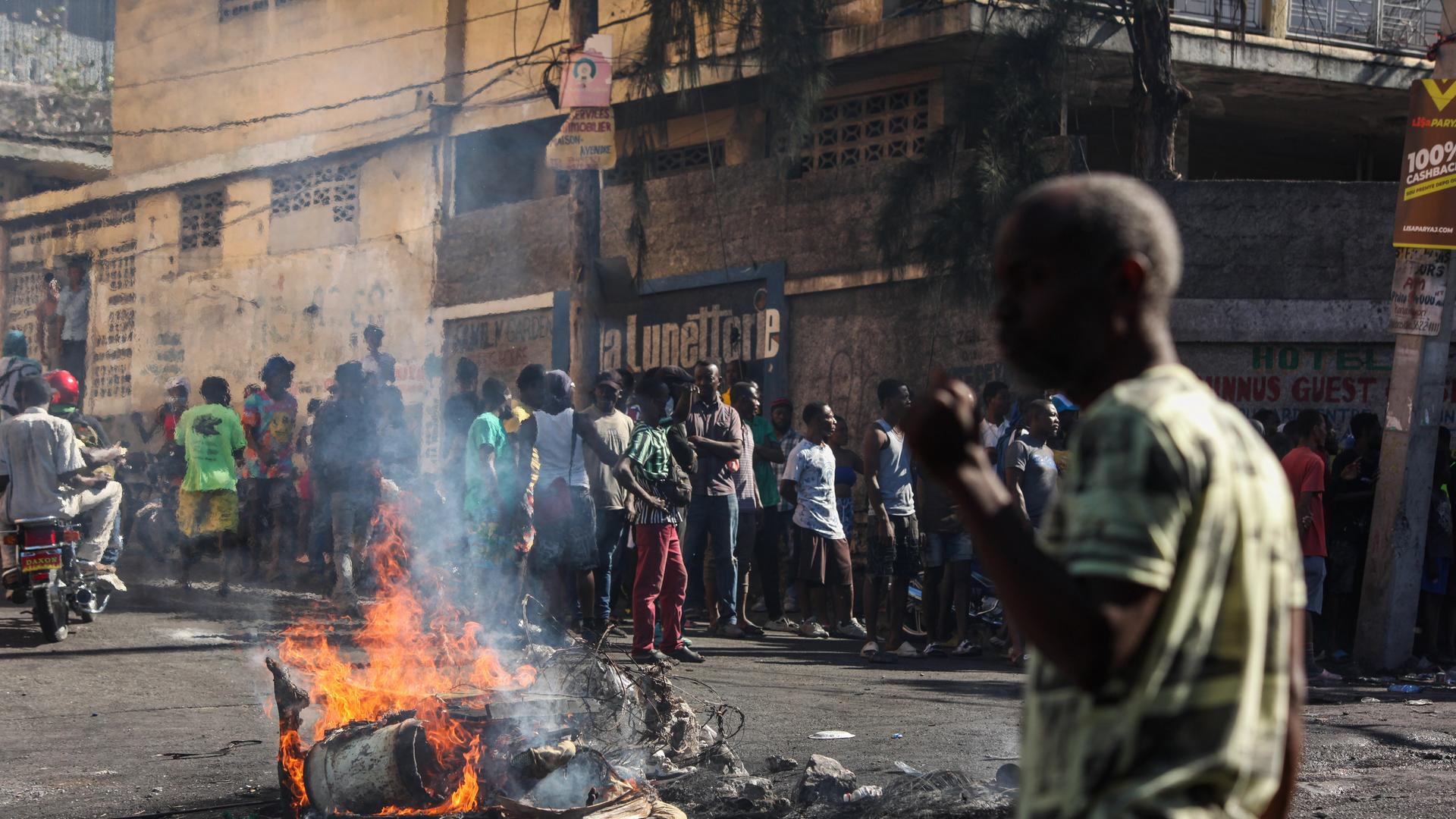 Ein Foto zeigt eine brennende Barrikade und zahlreiche Menschen drumherum in Haitis Hauptstadt Port au Prince.