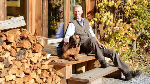 Förster und Unternehmer Erwin Thoma sitzt mit seinem Hund vor seinem Haus.
