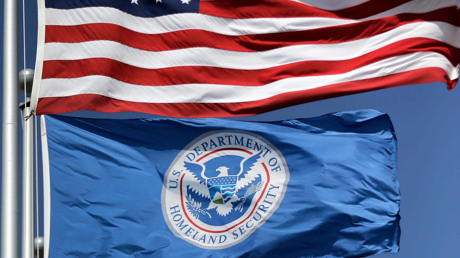 Die Fahnen der USA und der Heimatschutzbehörde wehen untereinander. Die Fahnen der USA und der Heimatschutzbehörde wehen untereinander.