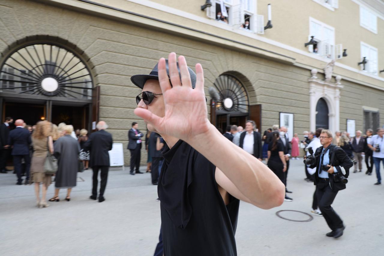 Teodor Currentzis läuft mit erhobener Hand, um sich vor Fotografen zu schützen, zu den Salzburger Festspielen 2021.