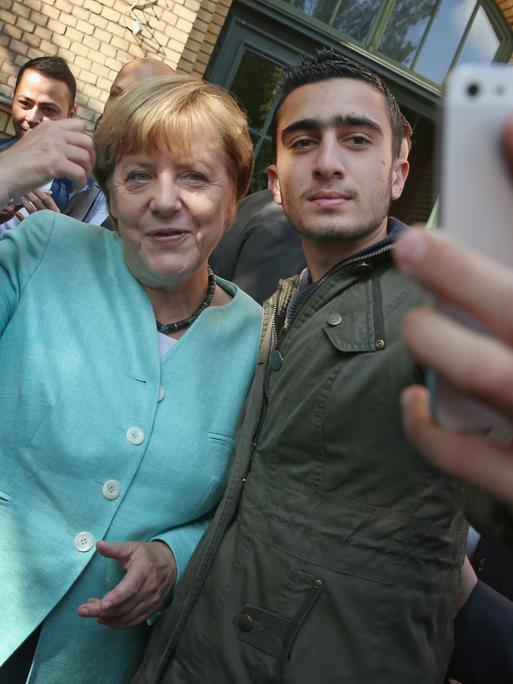 Bundeskanzlerin Angela Merkel posiert für ein Selfie mit Anas Modamani, einem Flüchtling aus Syrien, nachdem sie das AWO Refugium Askanierring, eine Unterkunft für Migranten und Flüchtlinge, am 10. September 2015 in Berlin, Deutschland, besucht hat. 