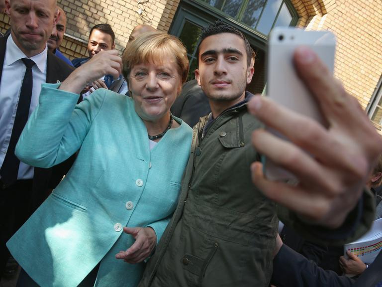Bundeskanzlerin Angela Merkel posiert für ein Selfie mit Anas Modamani, einem Flüchtling aus Syrien, nachdem sie das AWO Refugium Askanierring, eine Unterkunft für Migranten und Flüchtlinge, am 10. September 2015 in Berlin, Deutschland, besucht hat. 