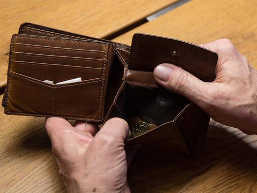 Hände halten ein geöffnetes Portemonnaie in der Hand.