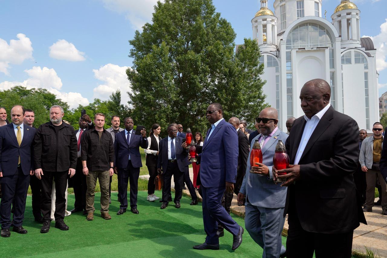 Die afrikanische Vermittlerdelegation, angeführt von Südafrikas Präsident Ramaphosa kommt, in Bucha an. Hiter ihnen eine große weiße Kathedrale.