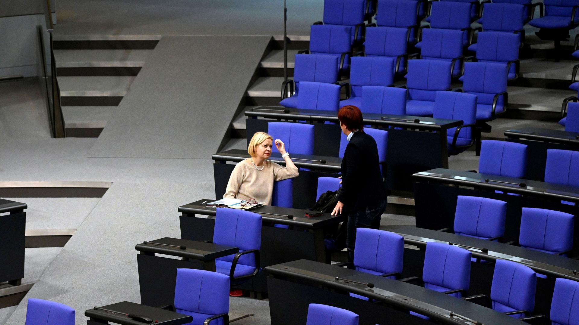 Gesine Lötzsch sitzt im Bundestag, eine Person steht neben ihr, sonst leere Sitze. Es ist die 135. Sitzung des Deutschen Bundestages, 10.11.2023.