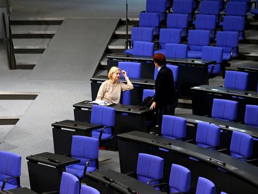 Gesine Lötzsch sitzt im Bundestag, eine Person steht neben ihr, sonst leere Sitze. Es ist die 135. Sitzung des Deutschen Bundestages, 10.11.2023.