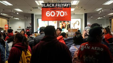 Ein Laden ist voll von Kunden. Über ihnen ein Plakat mit der Aufschrift "Black Friyay!"