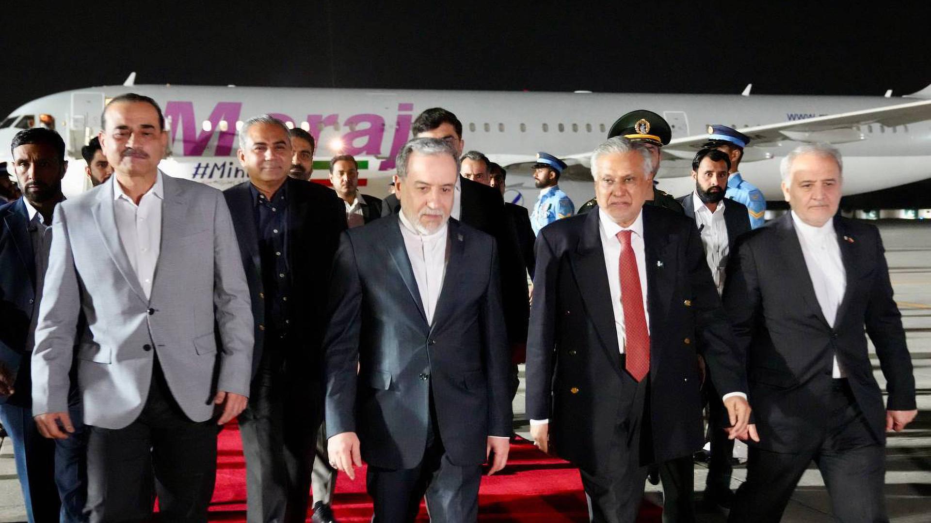 Mehrere Männer laufen über einen roten Teppich auf einem Rollfeld eines Flughafens. Es ist Nacht.