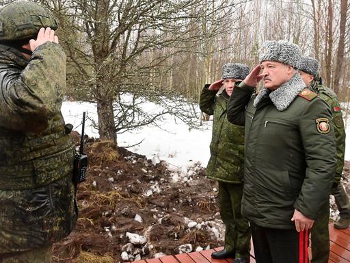 Alexander Lukaschenko in einer Militäruniform grüßt einen Angehörigen der Armee.