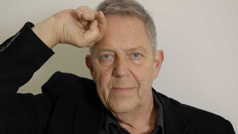 Portraitaufnahme des inzwischen verstorbenen Dichters Robert Gernhardt, eine Hand ist an die Stirn gelegt.