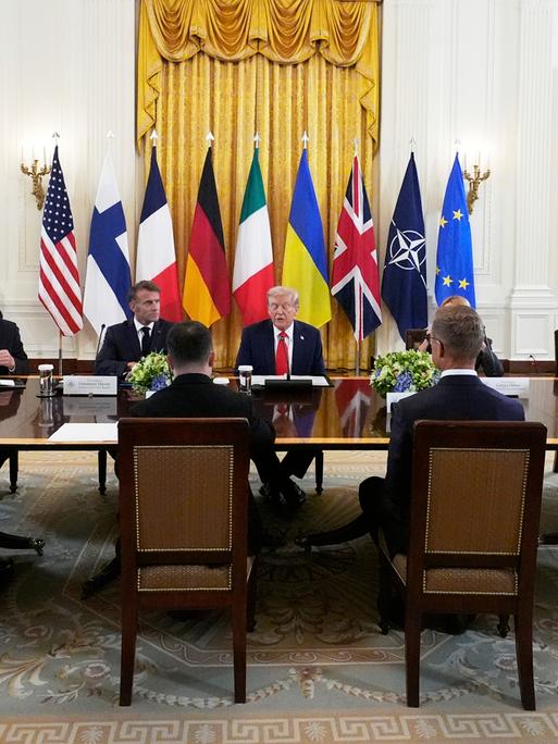 Donald Trump sitzt an einem Tisch mit dem britischen Premier Keir Starmer, Frankreichs Präsident Emmanuel Macron, Bundeskanzler Friedrich Merz, Ukraines Präsident Wolodymyr Selenskyj und EU-Kommissionspräsidentin Ursula von der Leyen