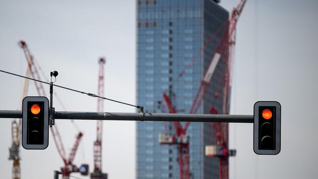 Rot zeigende Ampeln vor der Kulisse von Kränen auf einer Baustelle am Alexanderplatz in Berlin.
