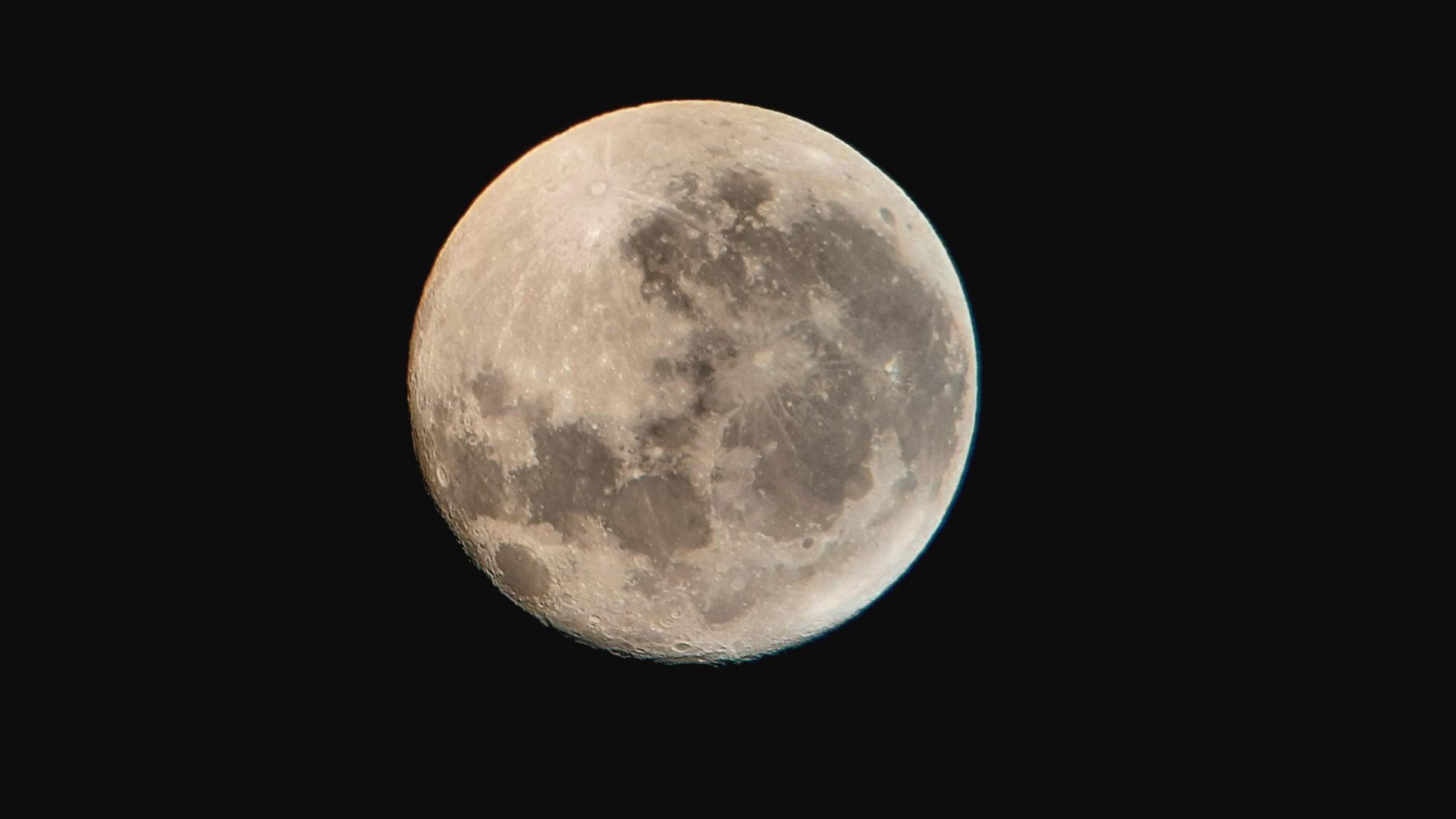 Ein fast voller Mond am schwarzen Nachthimmel.