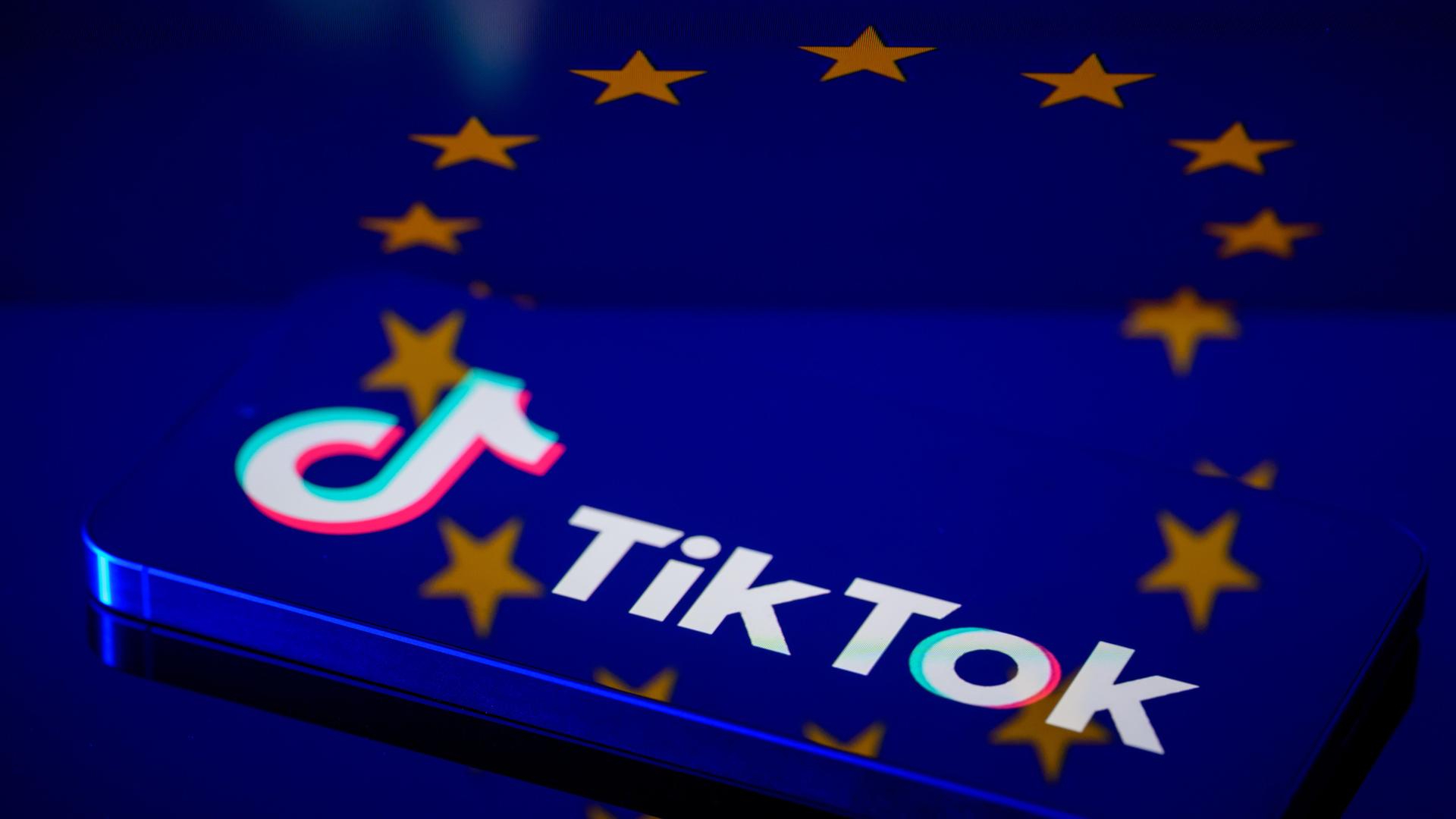Das TikTok-Logo auf einem Smartphone, dahinter die europäische Flagge