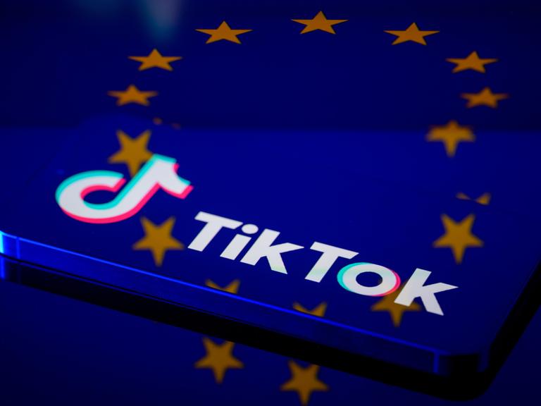 Das TikTok-Logo auf einem Smartphone, dahinter die europäische Flagge Das TikTok-Logo auf einem Smartphone, dahinter die europäische Flagge