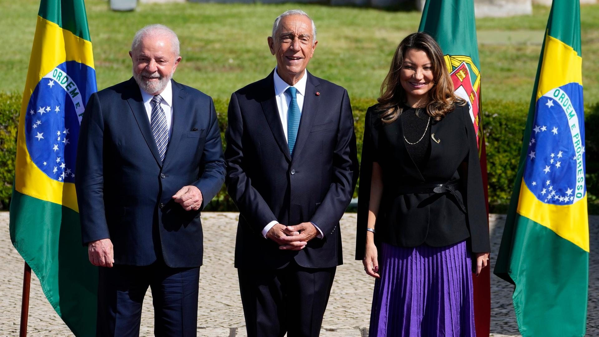 Marcelo Rebelo de Sousa (in der Mitte), Präsident von Portugal, steht zwischen Luiz Inacio Lula da Silva (links), Präsident von Brasilien, und dessen Ehefrau Rosangela da Silva. Hinter ihnen stehen die Landesfahnen.