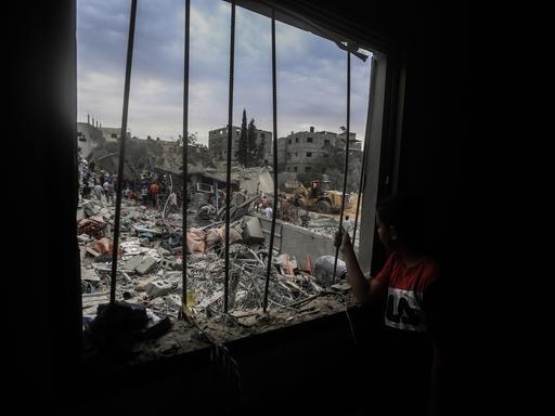Ein junger Mann schaut aus einem vergitterten Fenster auf Trümmer, in Chan Yunis im südlichen Teil des Gaza-Streifens