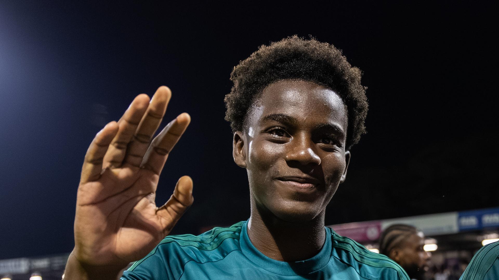 Jadiel Pereira im Fußball-Stadion. Er trägt das Trikot von seinem Verein PEC Zwolle. Pereira lächelt in die Kamera und hebt die Hand. 