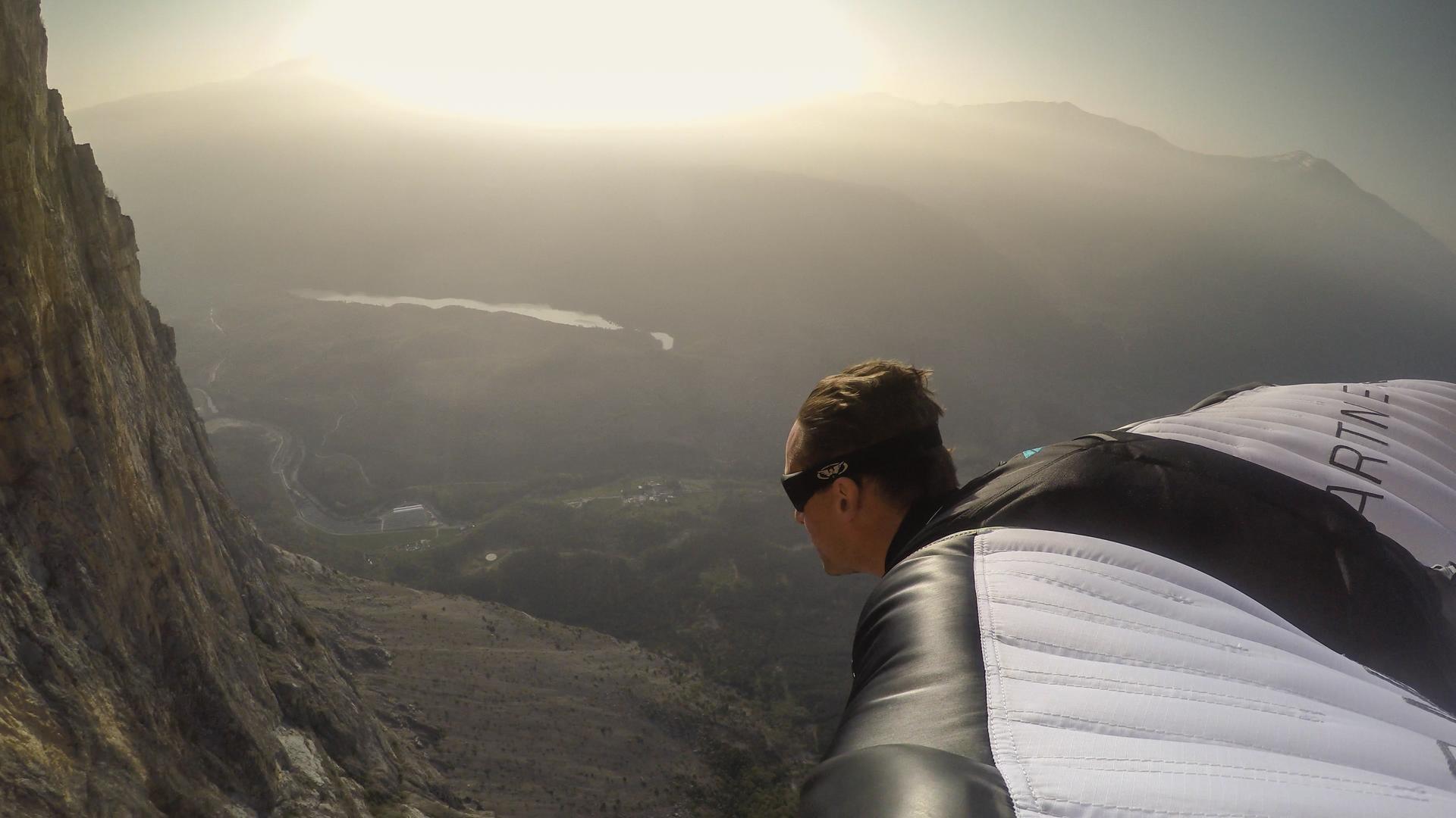 Der Basejumper Maximilian Werndl beim Flug in einem drachenartigen Anzug (Wingsuit) vor einem Bergpanorama im Gegenlicht. Der Basejumper Maximilian Werndl beim Flug in einem drachenartigen Anzug (Wingsuit) vor einem Bergpanorama im Gegenlicht.