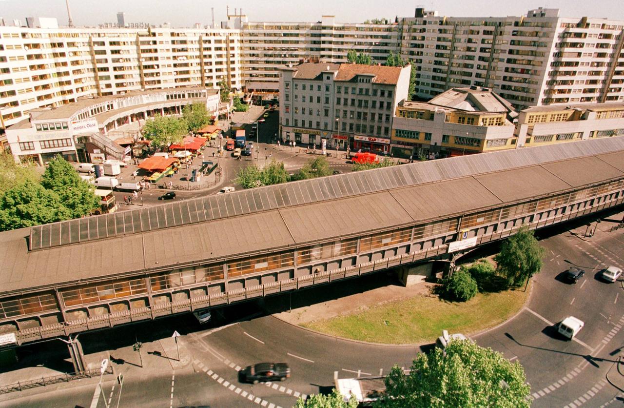 Eine Hochhausanlage, davor die Gleise und der Bahnhof einer Hochbahn.