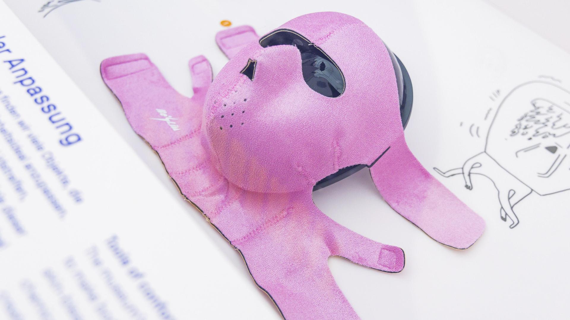 Eine rosafarbene Gesichtsmaske liegt ausgebreitet auf einem Ausstellungstisch.