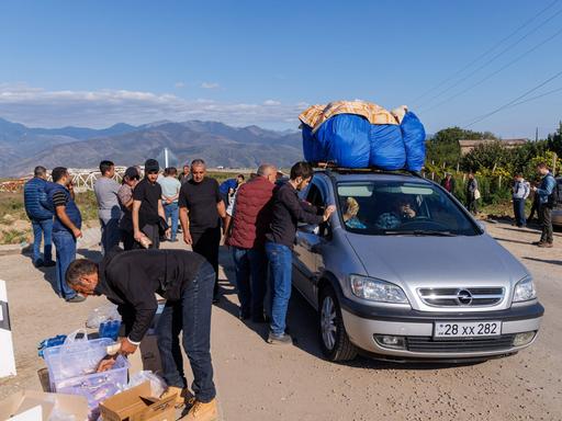 Flüchtlinge aus Bergkarabach stehen an einem vollgepackten Auto.