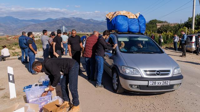 Das Foto zeigt armenische Flüchtlinge neben einem einem vollgepackten Auto.