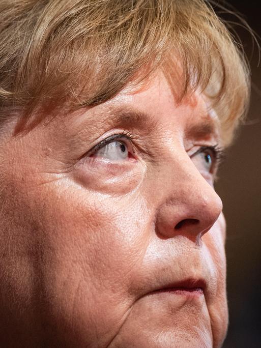 Leicht seitlich fotografierte Nahaufnahme von Angela Merkel mit einem ernsten und nachdebnklichen Gesichtsausdruck
