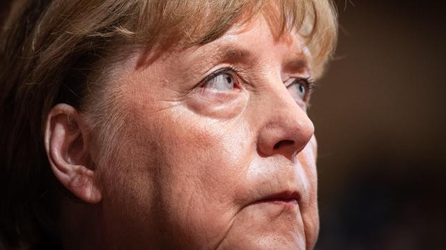 Leicht seitlich fotografierte Nahaufnahme von Angela Merkel mit einem ernsten und nachdebnklichen Gesichtsausdruck