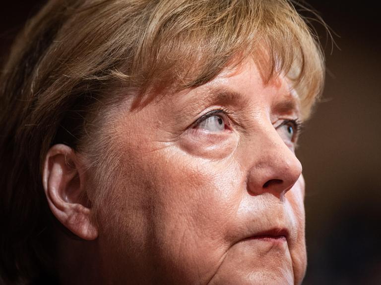 Leicht seitlich fotografierte Nahaufnahme von Angela Merkel mit einem ernsten und nachdebnklichen Gesichtsausdruck