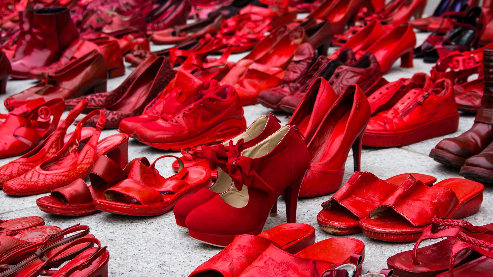 Auf einer Straße in der Nähe der Piazza Garibaldi in Gagliari auf Sardinien sind zahlreiche blutrot angemalte Schuhe aufgereiht.