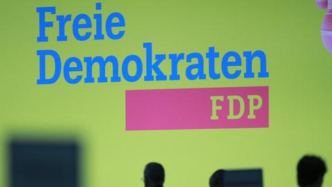 Bei einem Europaparteitag der FDP ist groß das Logo der FDP auf einer Wand zu sehen, im Vordergrund sieht man die Schatten von Delegierten.