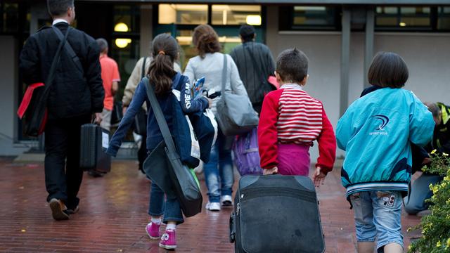 Geflüchtete aus dem Land Syrien kommen 2013 in einem Übergangs-Heim in dem Bundes-Land Niedersachsen an. Sie haben Roll-Koffer dabei. 