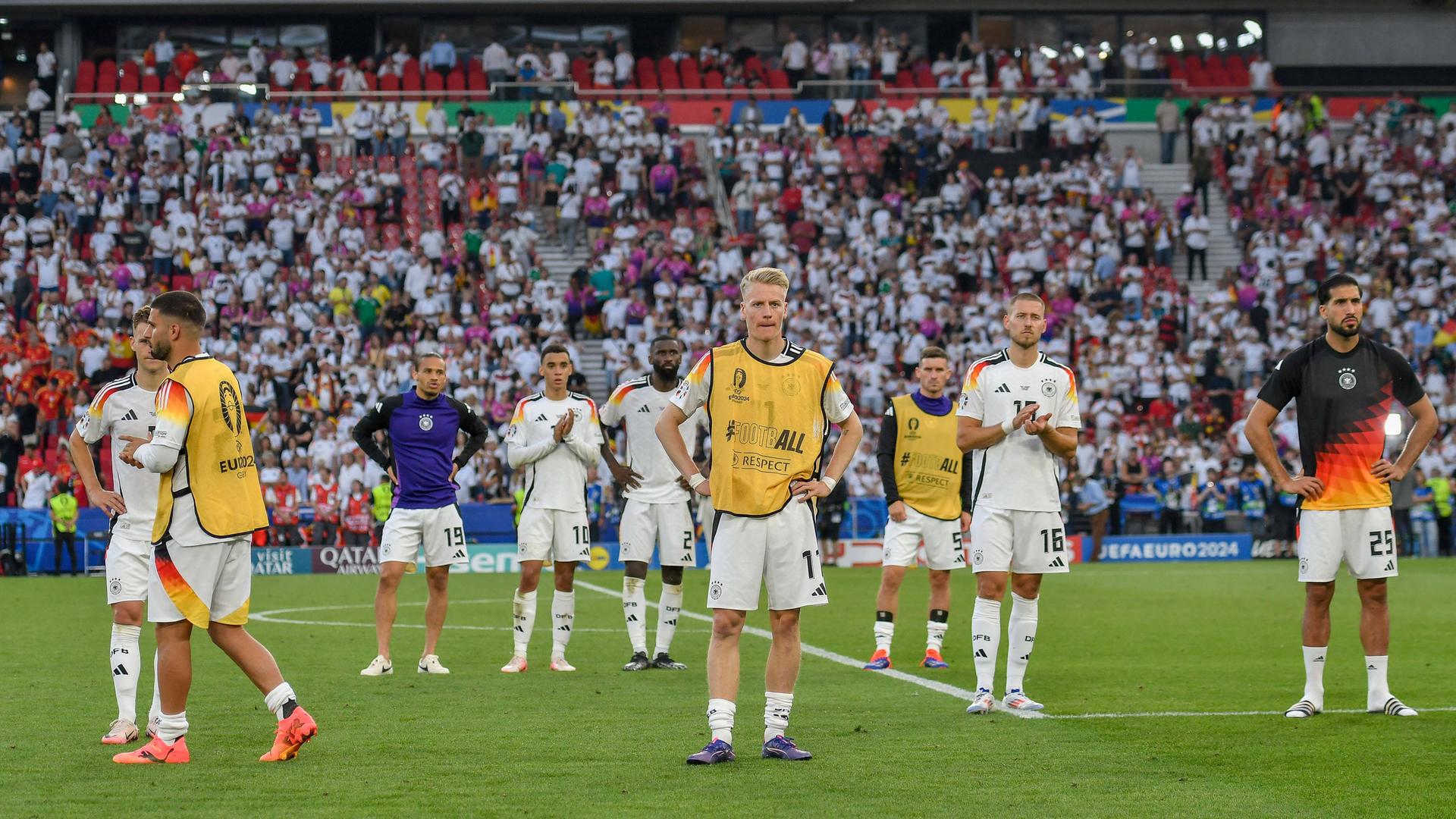 Spieler der deutschen Nationalmannschaft stehen auf dem Spielfeld in Stuttgart und schauen enttäuscht.
      
