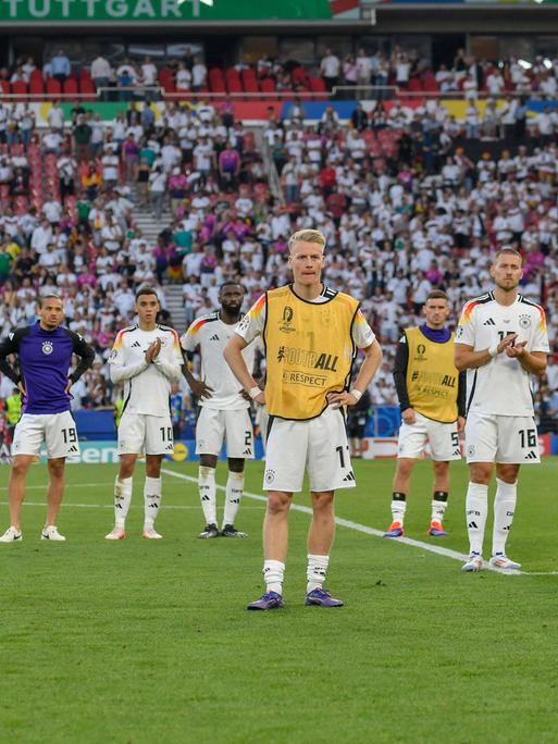 Spieler der deutschen Nationalmannschaft stehen auf dem Spielfeld in Stuttgart und schauen enttäuscht. 
