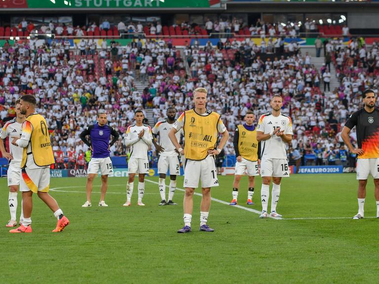 Spieler der deutschen Nationalmannschaft stehen auf dem Spielfeld in Stuttgart und schauen enttäuscht. 
