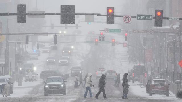 Fußgänger überqueren eine Straße während eines Winter-Sturms 