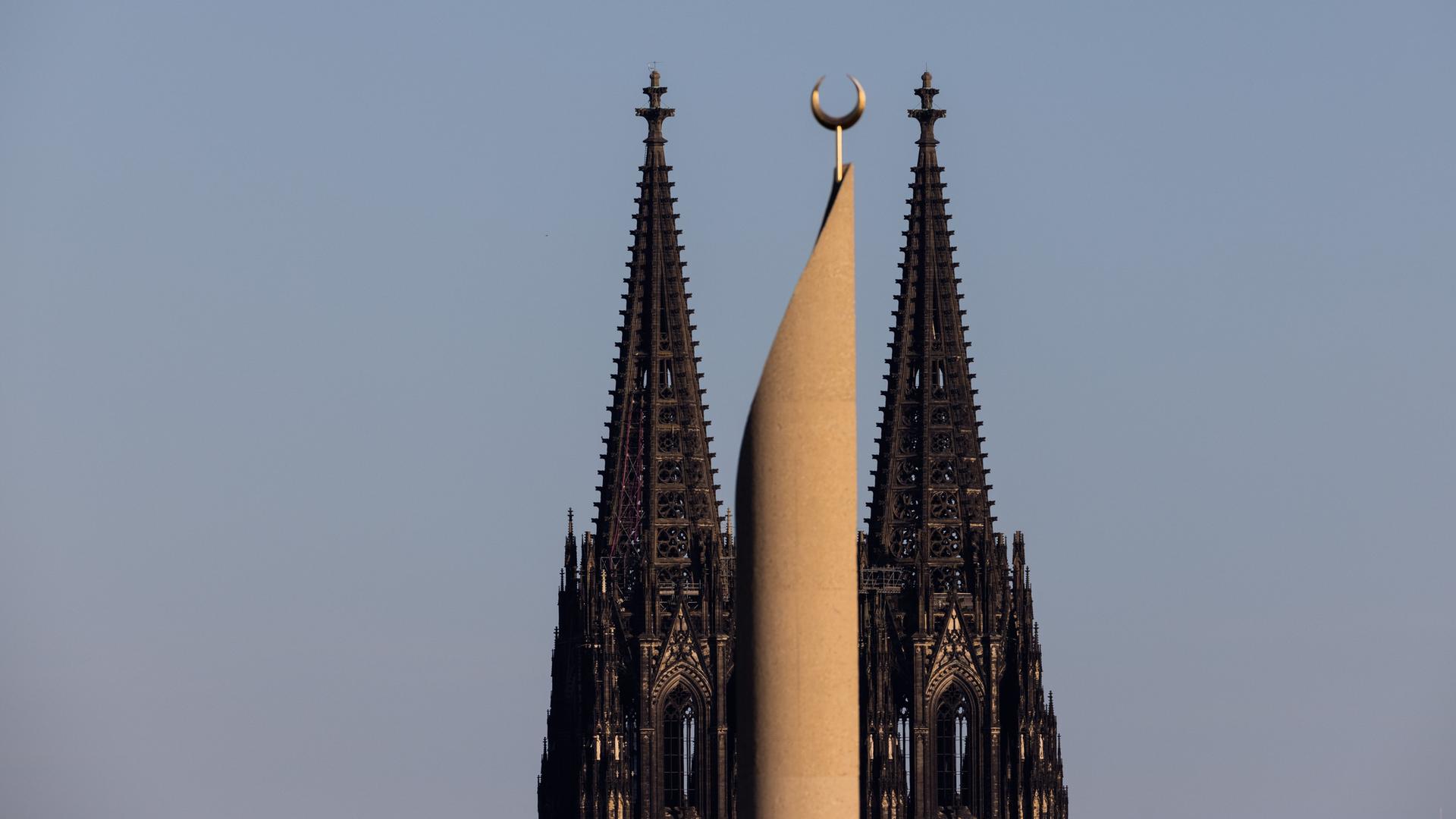 Im Licht in der untergehenden Sonne ist ein Minarett der Zentralmoschee der DITIB (Türkisch-Islamische Union der Anstalt für Religion) und der Kölner Dom zu sehen.