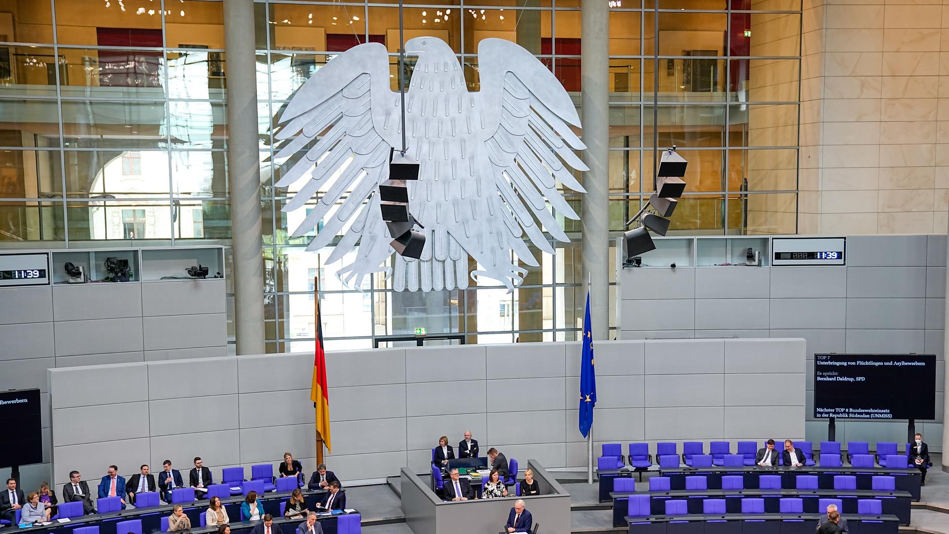 Der Plenarsaal des Deutschen Bundestages mit den blauvioletten Stühlen, Abgeordneten und dem großen Bundestagsadler (Fette Henne) im Berliner Reichstagsgebäude.