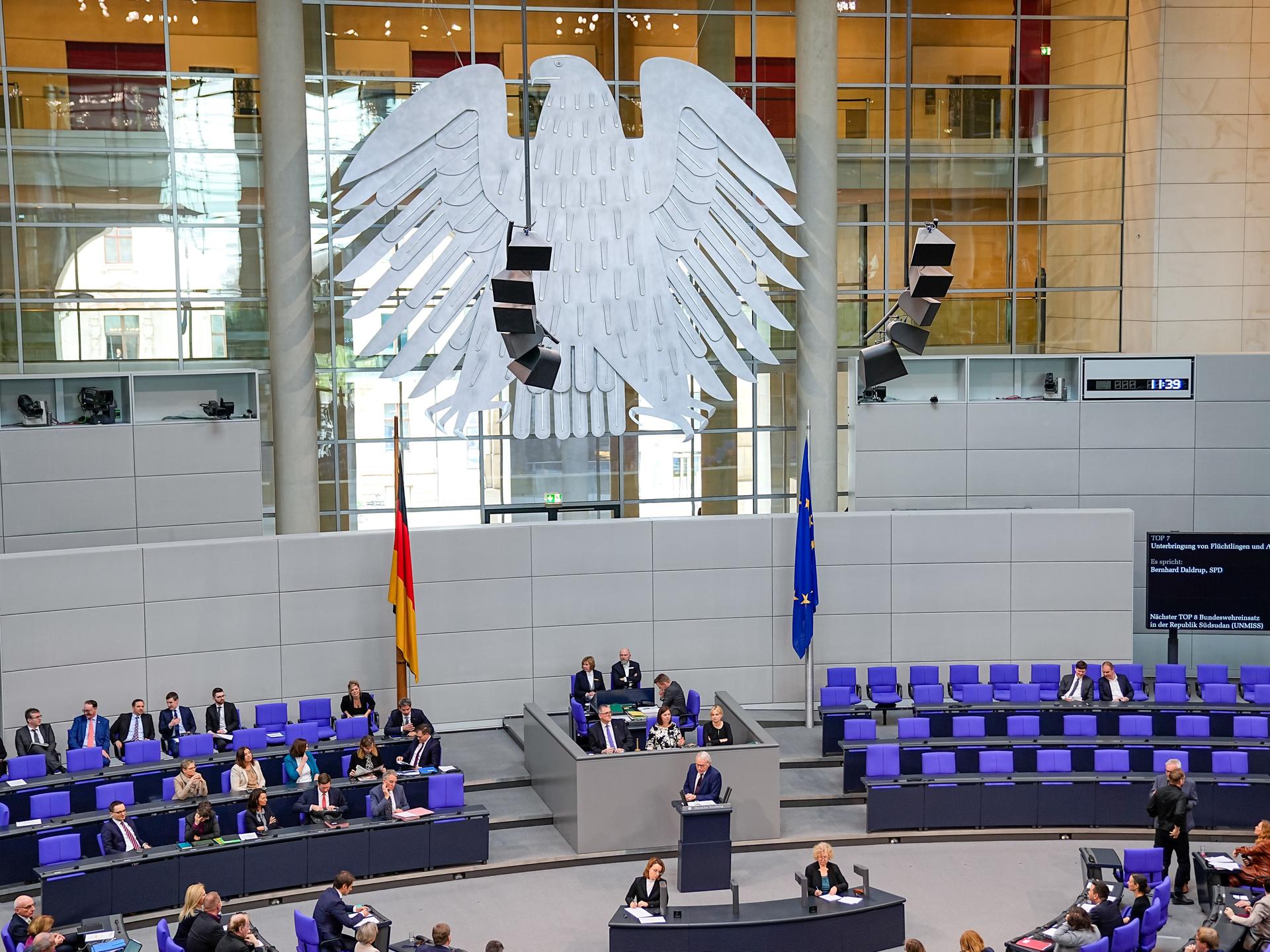 Der Plenarsaal des Deutschen Bundestages mit den blauvioletten Stühlen, Abgeordneten und dem großen Bundestagsadler (Fette Henne) im Berliner Reichstagsgebäude.